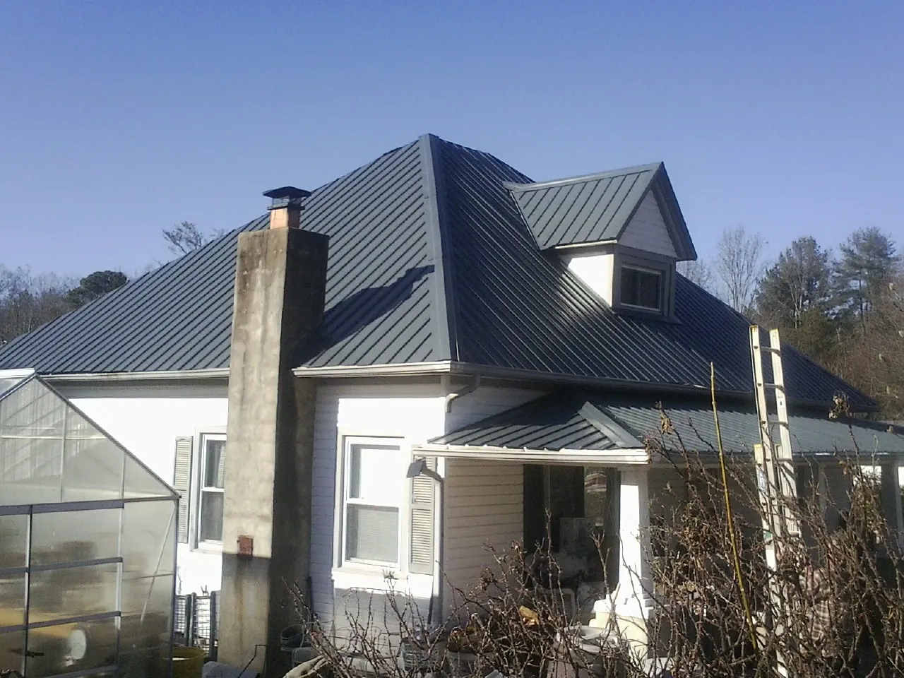 Dark blue standing seam metal roof on a white farmhouse with dormer — Slate & Tile Roof Repair by Roofing Brothers in Goshen