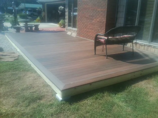 New wood deck and wicker chair beside a brick house in Goshen